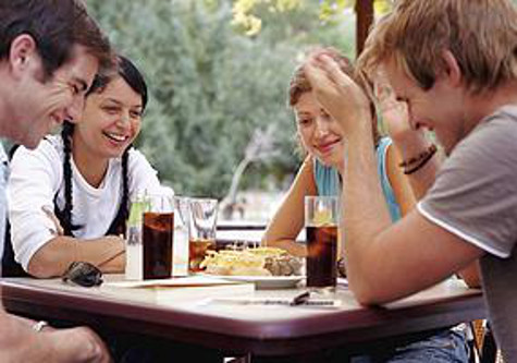 Two couples relaxing at outdoor cafe, smiling